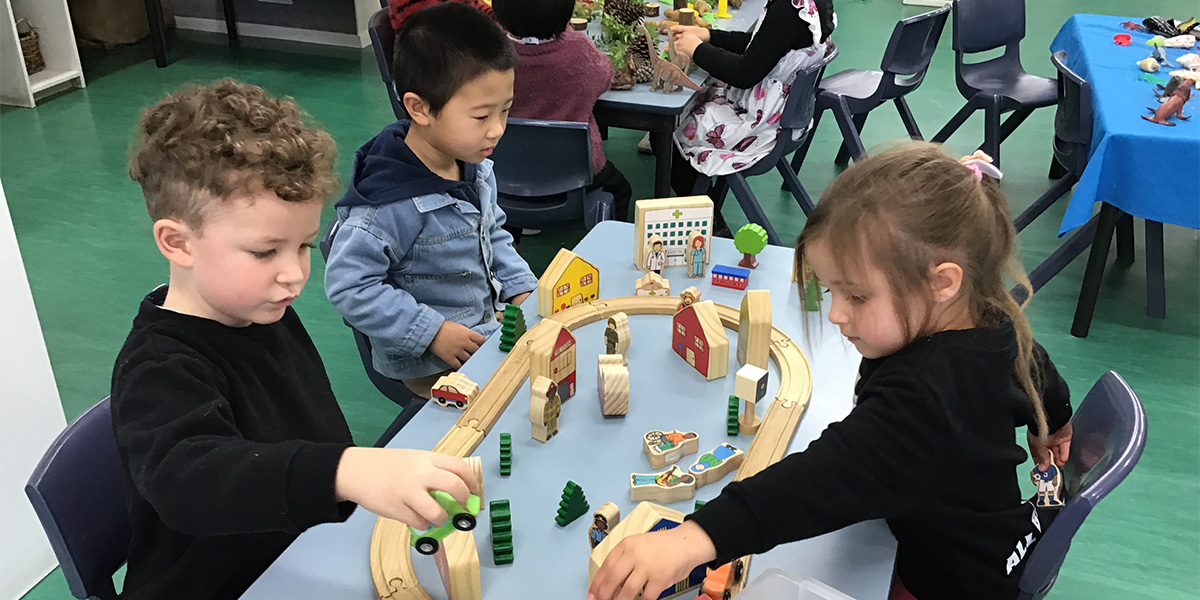 Three friends playing wooden cars 